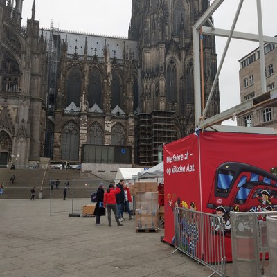 Der Vorplatz vom Dom mit einem karnevalistisch gestalteten Tolietten Areal in rot mit "Mer fahre af - op Kösche Aat."