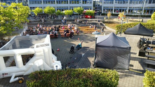 FrOSCon Social Event, Menschen auf Bierbänken im Innenhof der Hochschule Bonn-Rhein-Sieg