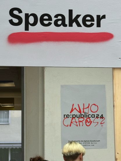 Speaker-Schild, dahinter Poster: rp24, Who cares. 