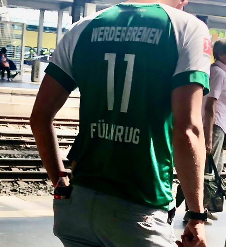 Ein Mann mit einem Niclas-Füllkrug-Trikot und einer Cola in der Hosentasche.