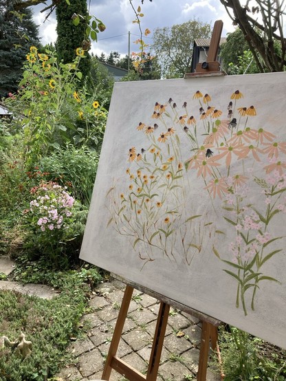 Du siehst im Vordergrund eine große Leinwand auf einer Staffelei. Darauf sind mit Ölfarbe Blüten skizziert, die bei mir links im Beet wachsen. Staudenphlox, Flohknöterich, Echinacea, Sommerbraut, Buschzinnien. 