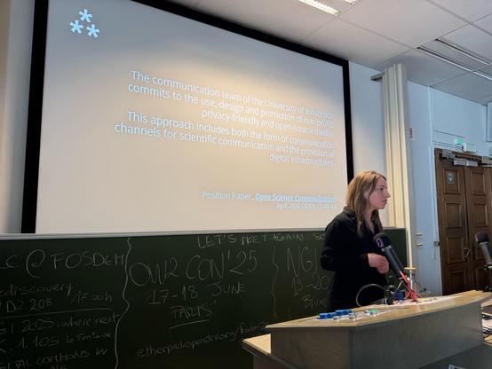 Melanie Bartos vor der Tafel mit dem Manifest der Uni Innsbruck für Open Science. 